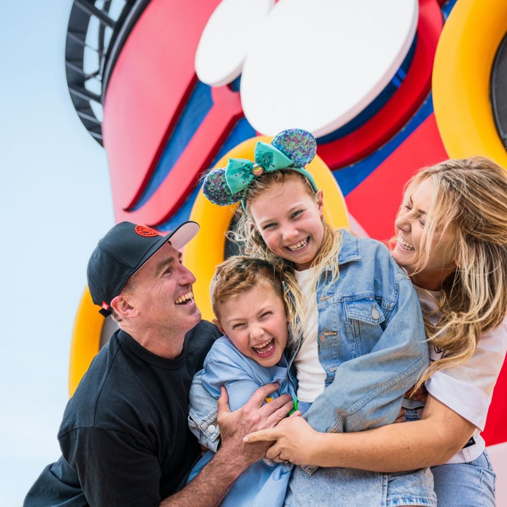 Uma família sorri e posa para uma foto a bordo do navio Disney Wonder