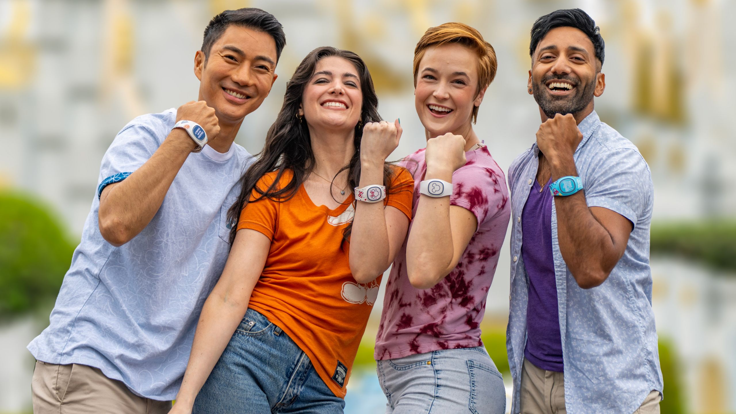 4 young adults smile while showing off their Disney Band Plus