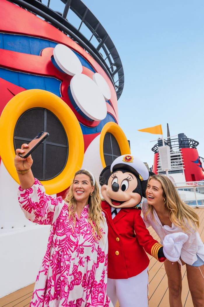 Two women taking a selfie with Captain Minnie on the deck of the Disney Magic ship