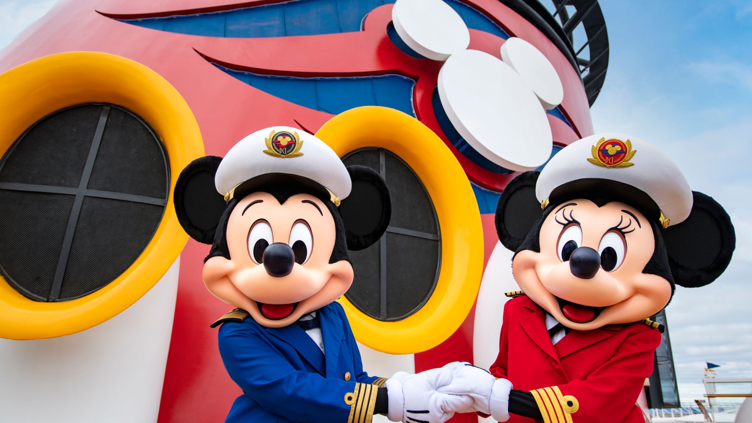 Mickey Mouse and Minnie Mouse dressed as captains and holding hands