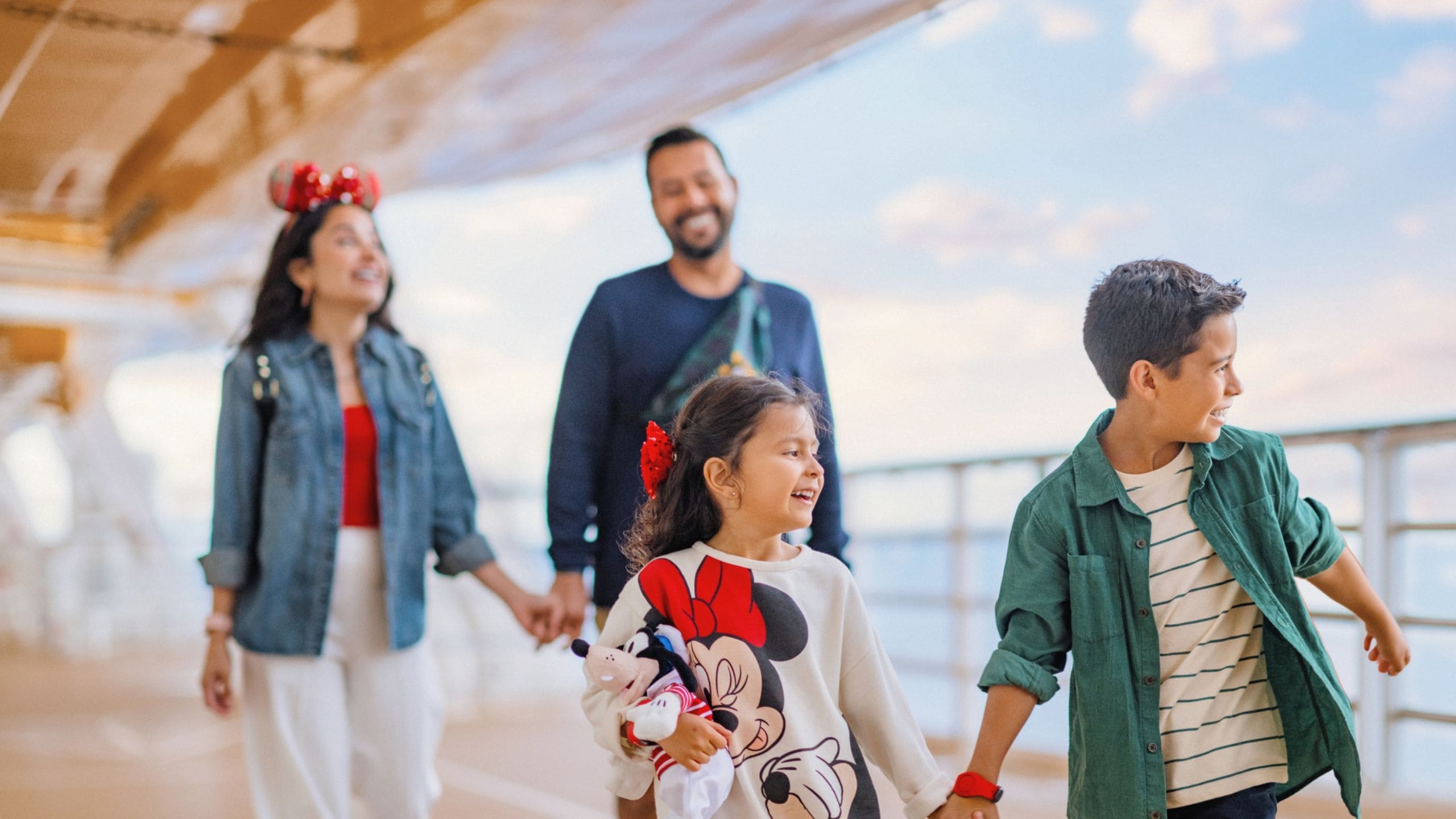 A young girl and boy walking along a deck and holding hands in front of their parents