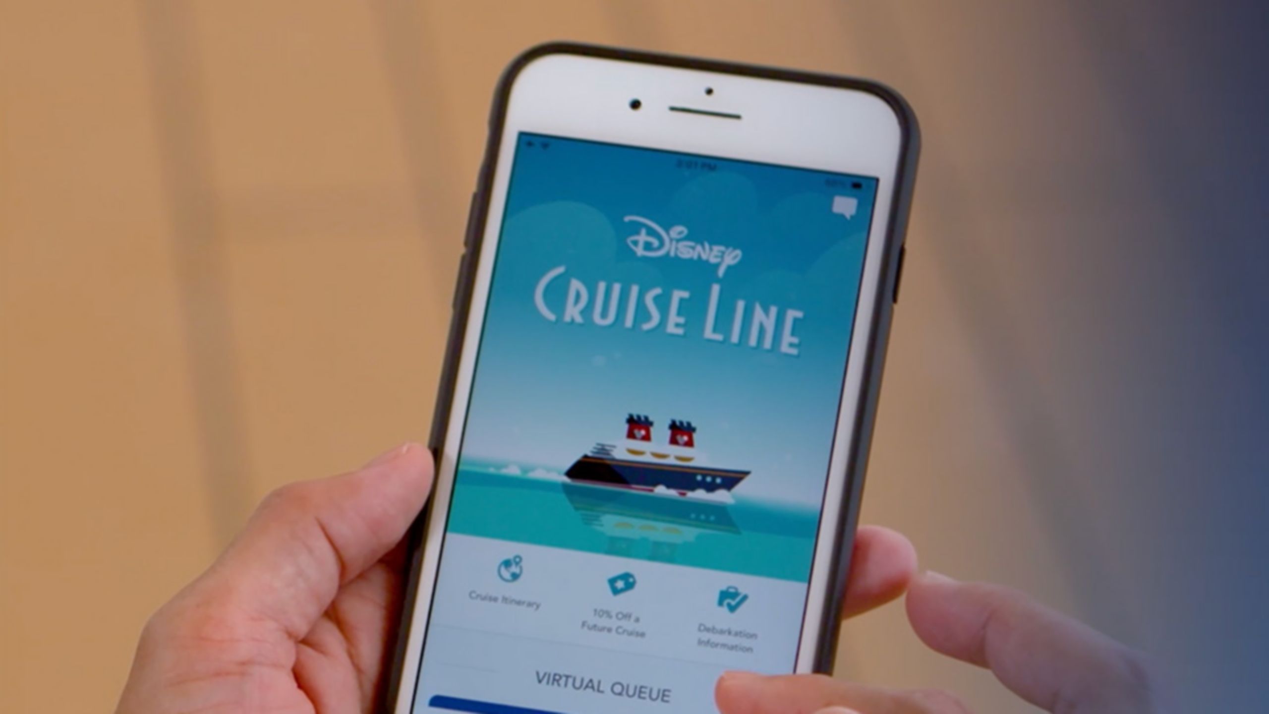 A hand holding a phone displaying the Disney Cruise Line Navigator app