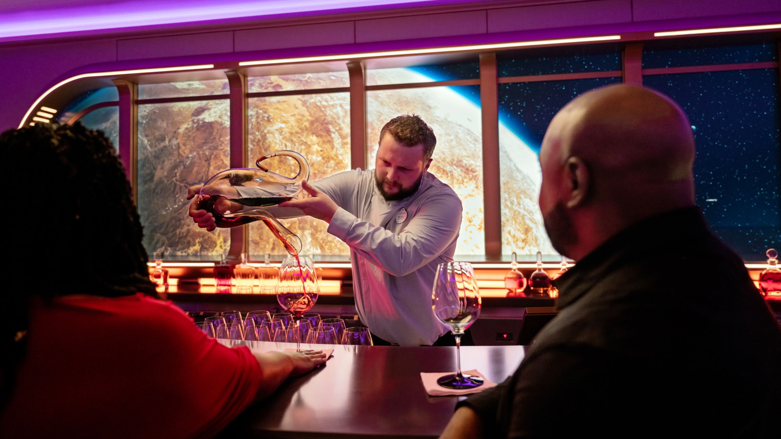 Cast Member pouring a drink for a couple at the bar of Star Wars: Hyperspace Lounge