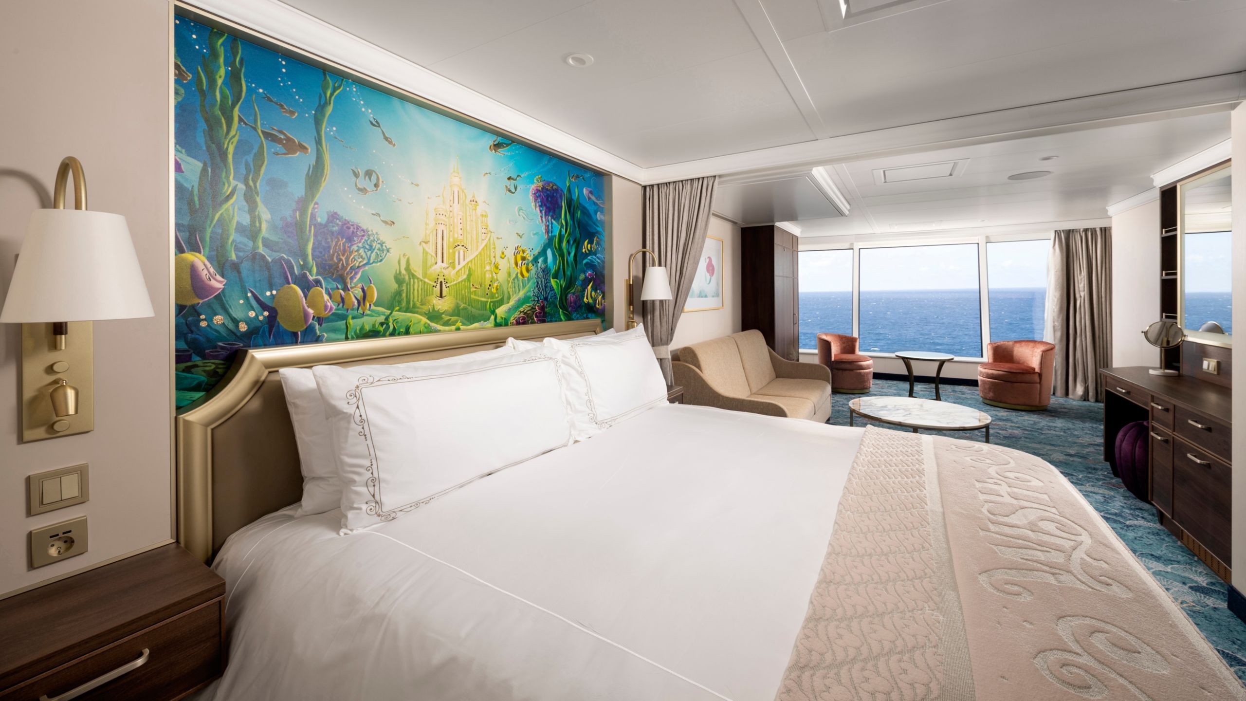 A Concierge stateroom featuring The Little Mermaid artwork and large windows overlooking the ocean