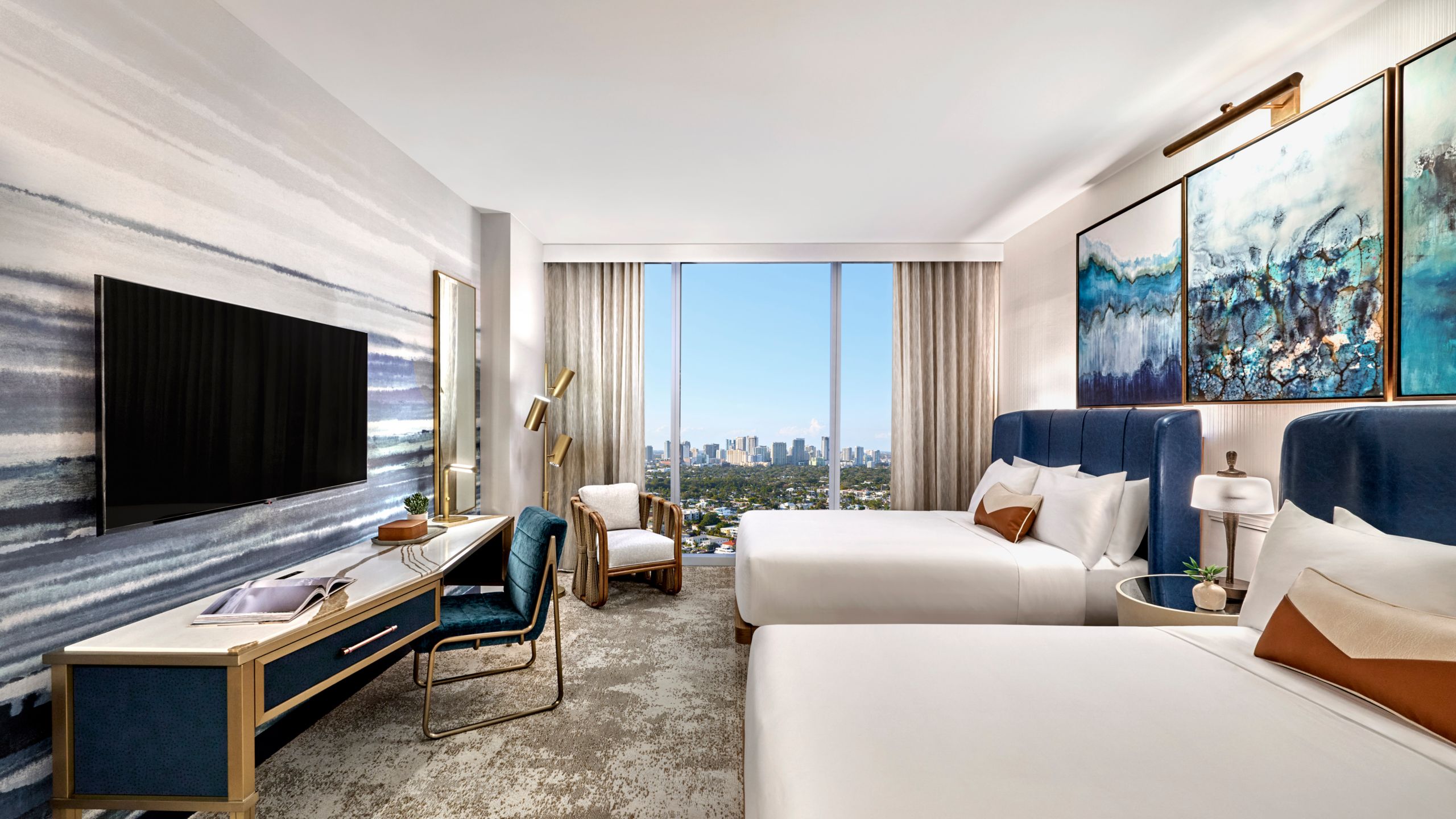 A rendering of a room in the Omni Fort Lauderdale Hotel with 2 beds, a console table, a TV, a cushioned chair and a window with city views