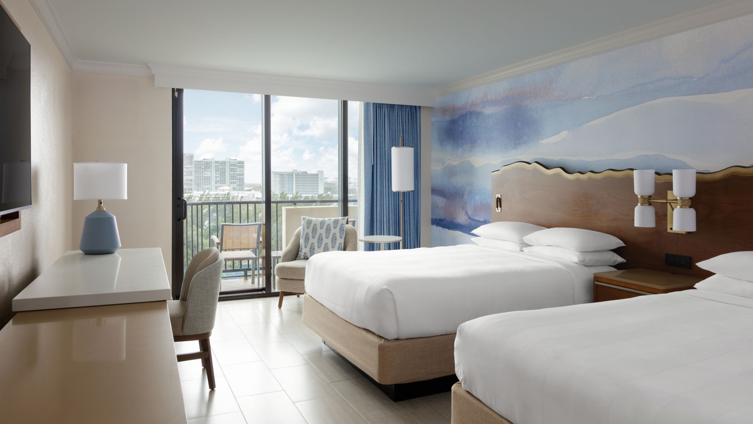 A room with 2 beds, a table, a chair and a window with resort views in the Fort Lauderdale Marriott Harbor Beach Resort & Spa