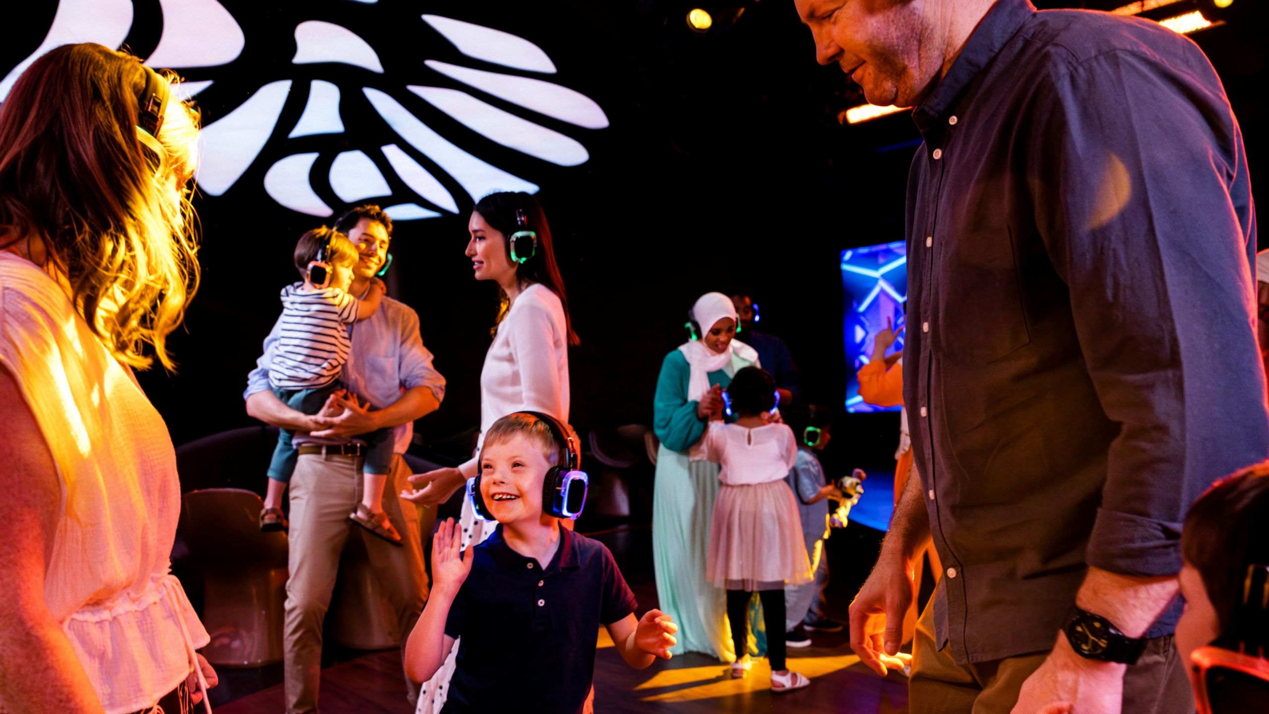 Volwassen en jonge gasten dansen tijdens een ‘silent disco’ in de D Lounge