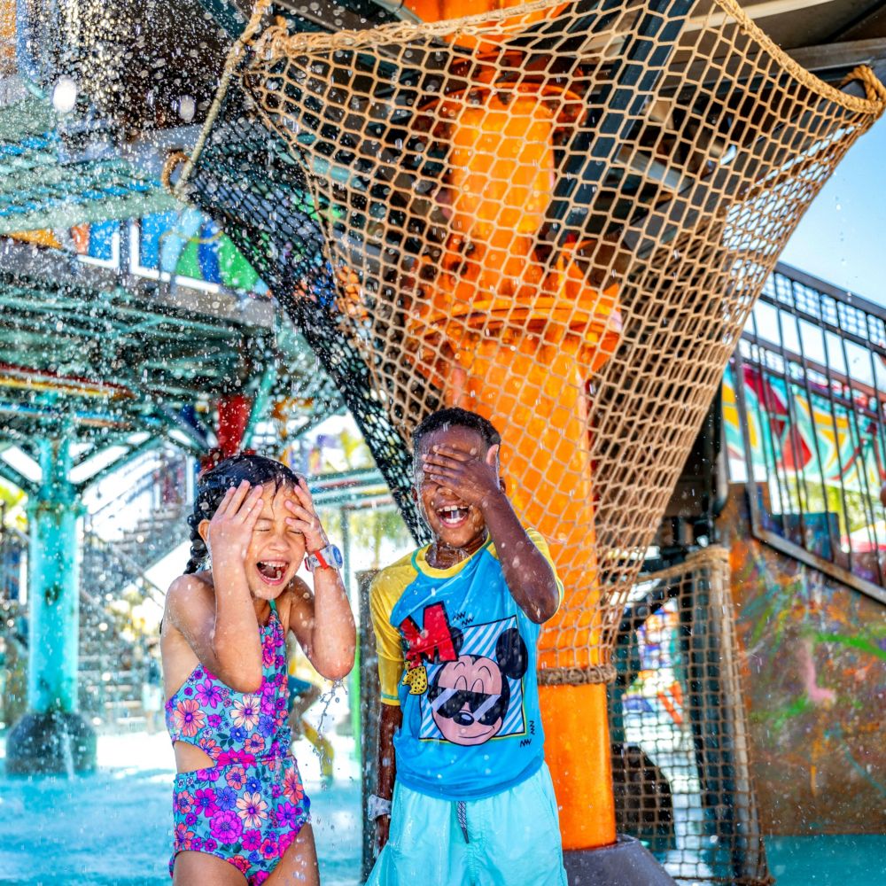 Dos niños jugando en la zona de juegos acuáticos Rush Out Gush Out en Disney Lookout Cay, en la Isla Privada Lighthouse Point