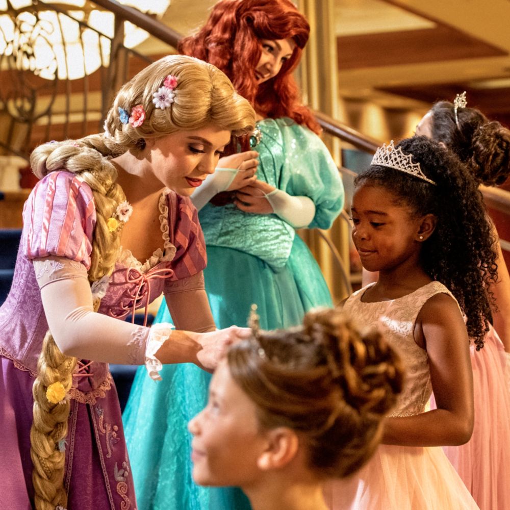 Niñas pequeñas con disfraces de princesas de la Bibbidi Bobbidi Boutique interactuando con Cenicienta, Rapunzel y Ariel