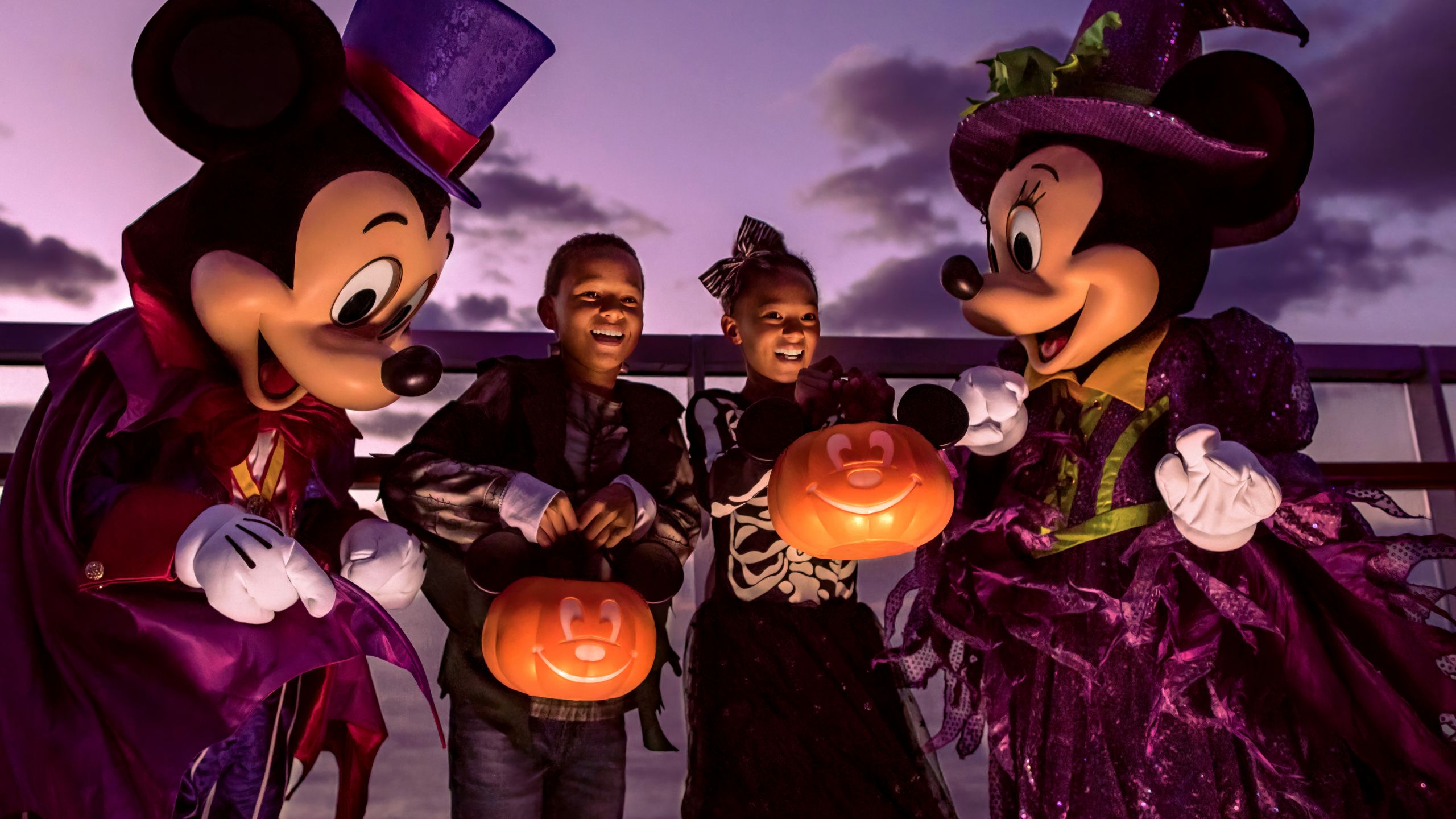 Mickey Mouse, Minnie Mouse, un niño y una niña con disfraces de Halloween en la cubierta de un crucero Disney
