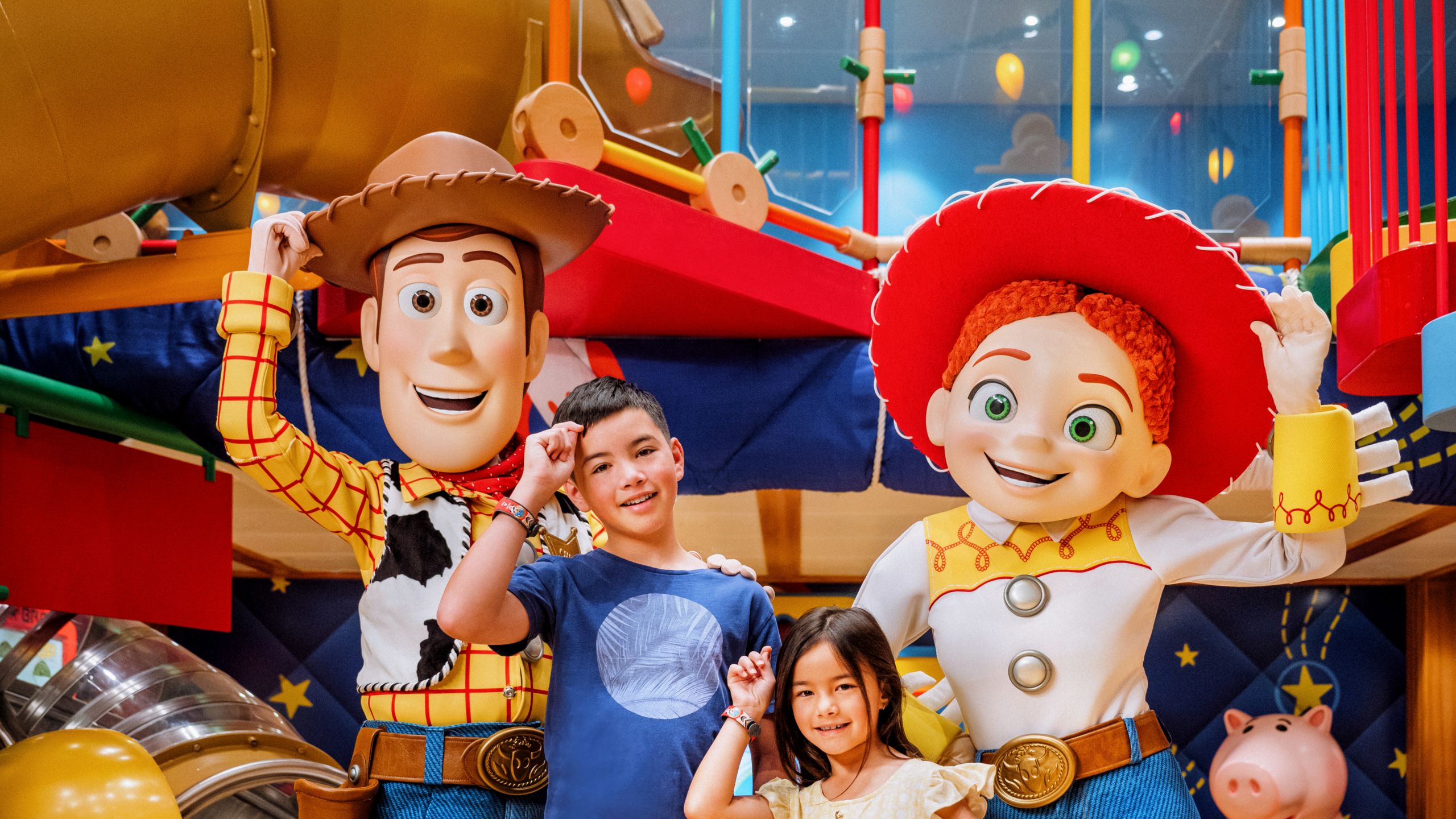 Un niño y una niña posando con Woody y Jessie en Andy’s Room en Disney’s Oceaneer Club