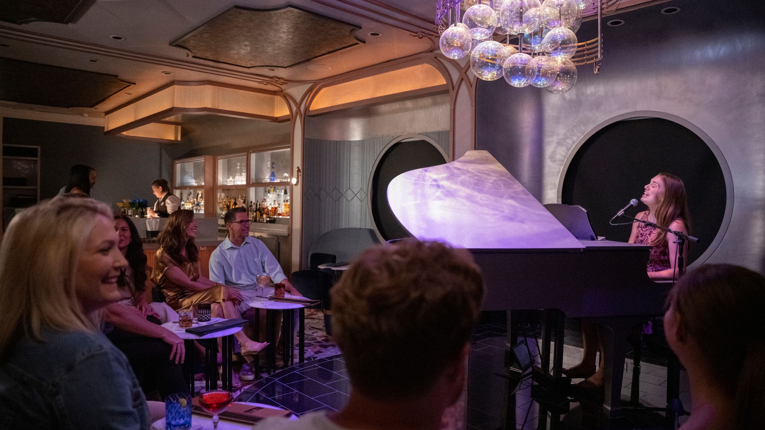 A female pianist sings and plays the piano in front of an audience at Nightingale's, a piano bar