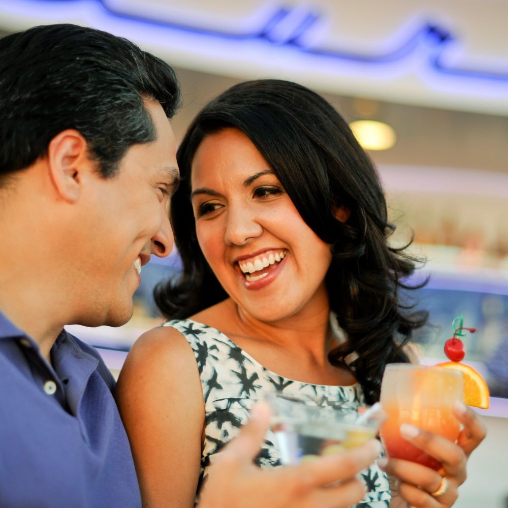 A smiling couple chats with cocktails in hand
