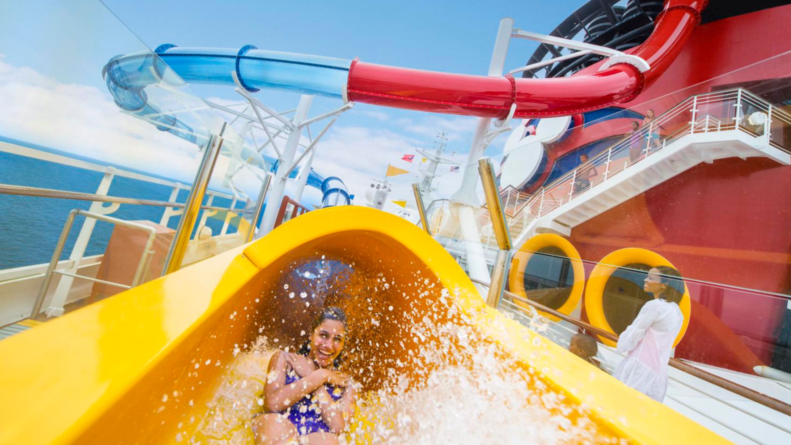A woman at the bottom of a waterslide on the deck of a Disney Cruise Line ship