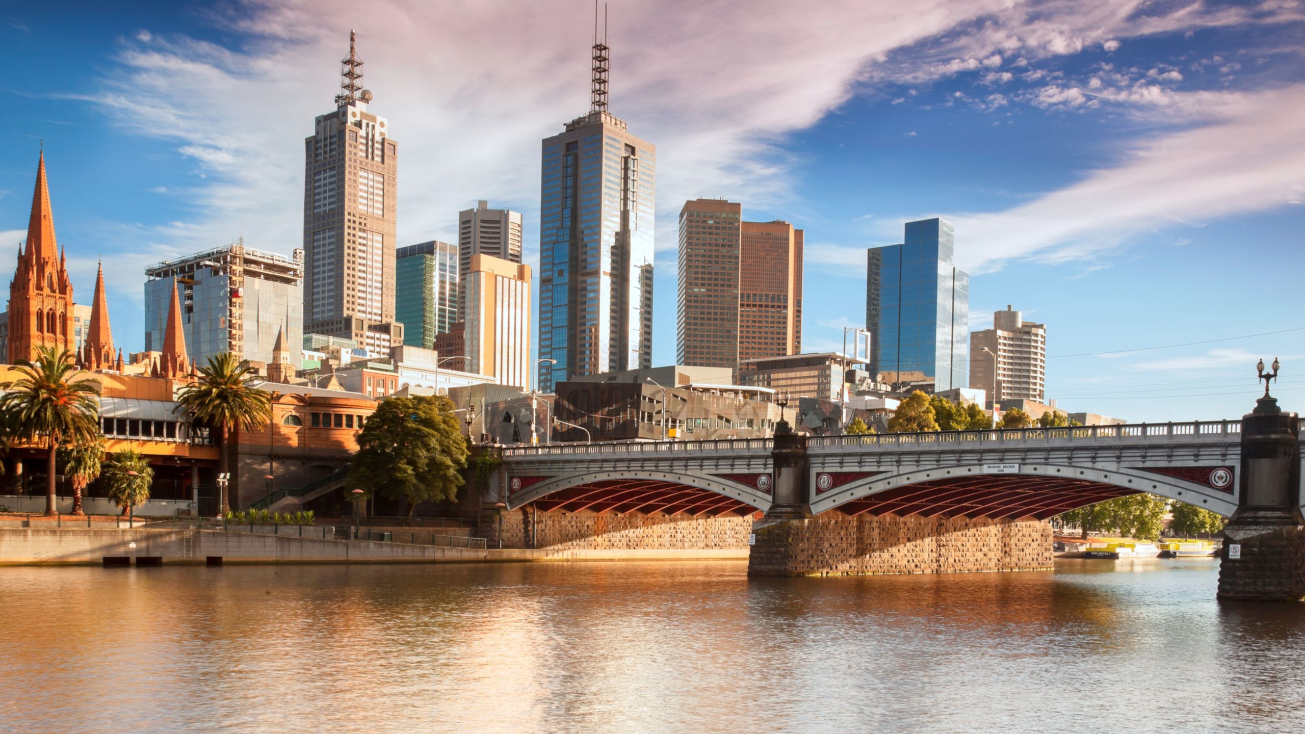The Melbourne cityscape reveals a vintage church and skyscrapers next to a river and bridge