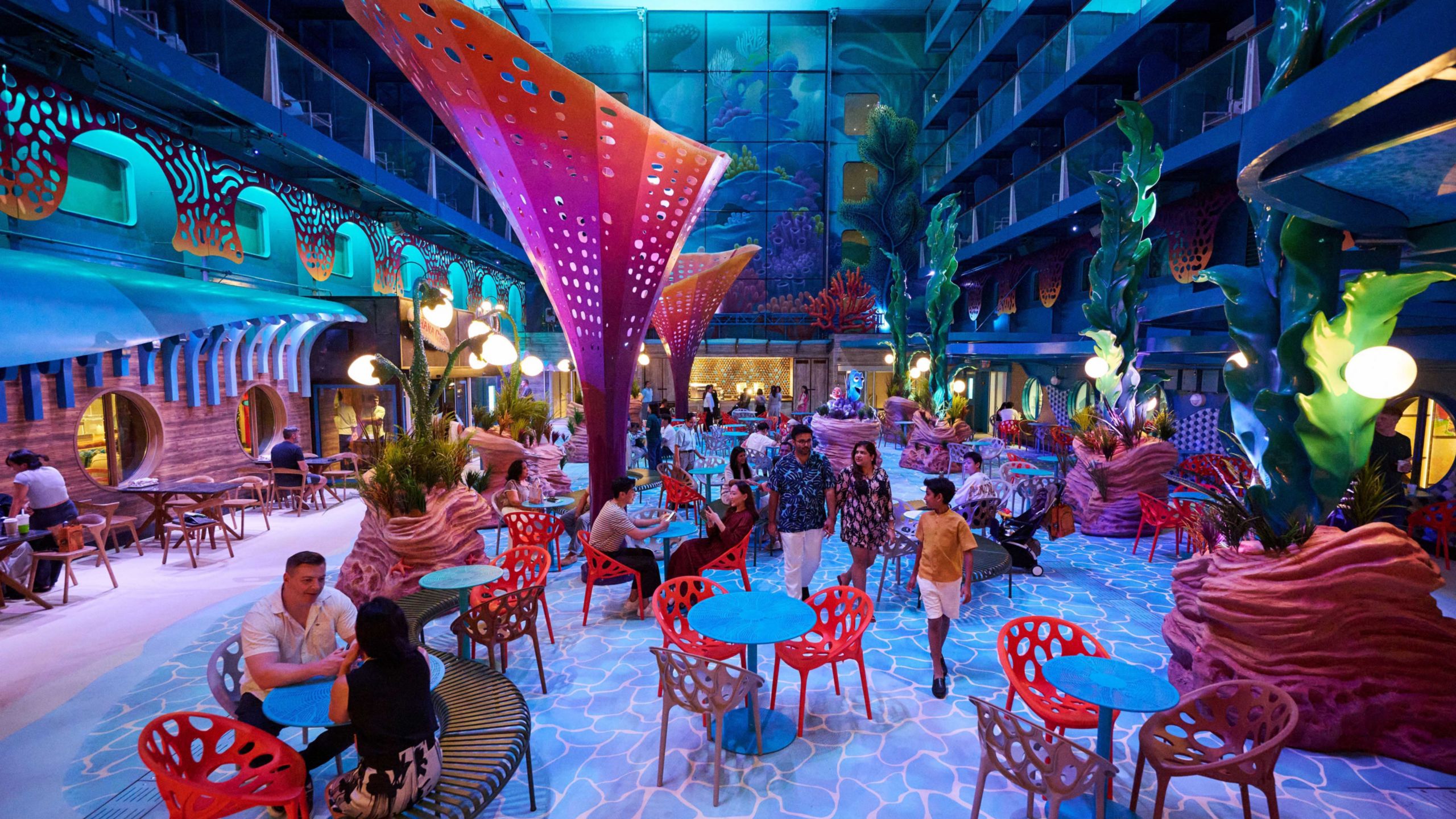 Guests dining and strolling in Disney Discovery Reef, an underwater themed area on the Disney Adventure cruise ship