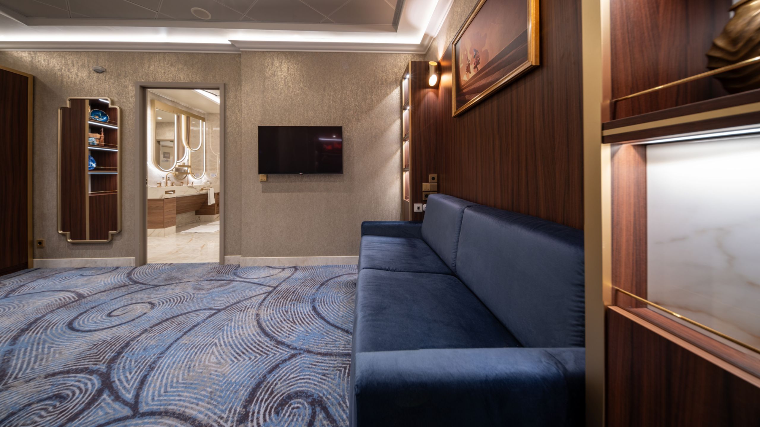 A room with a sofa, a mirror, a tv and a bathroom in a Disney Dream Concierge Dream Tower Suite