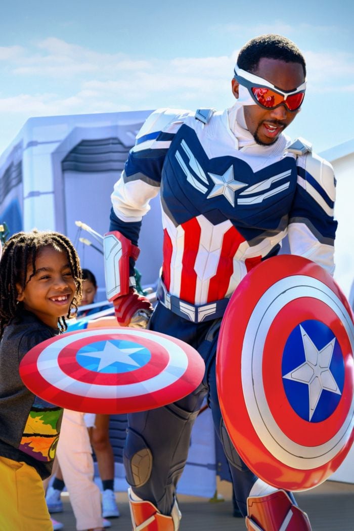 A young boy poses with Sam Wilson as Captain America, both of them holding Captain America shields