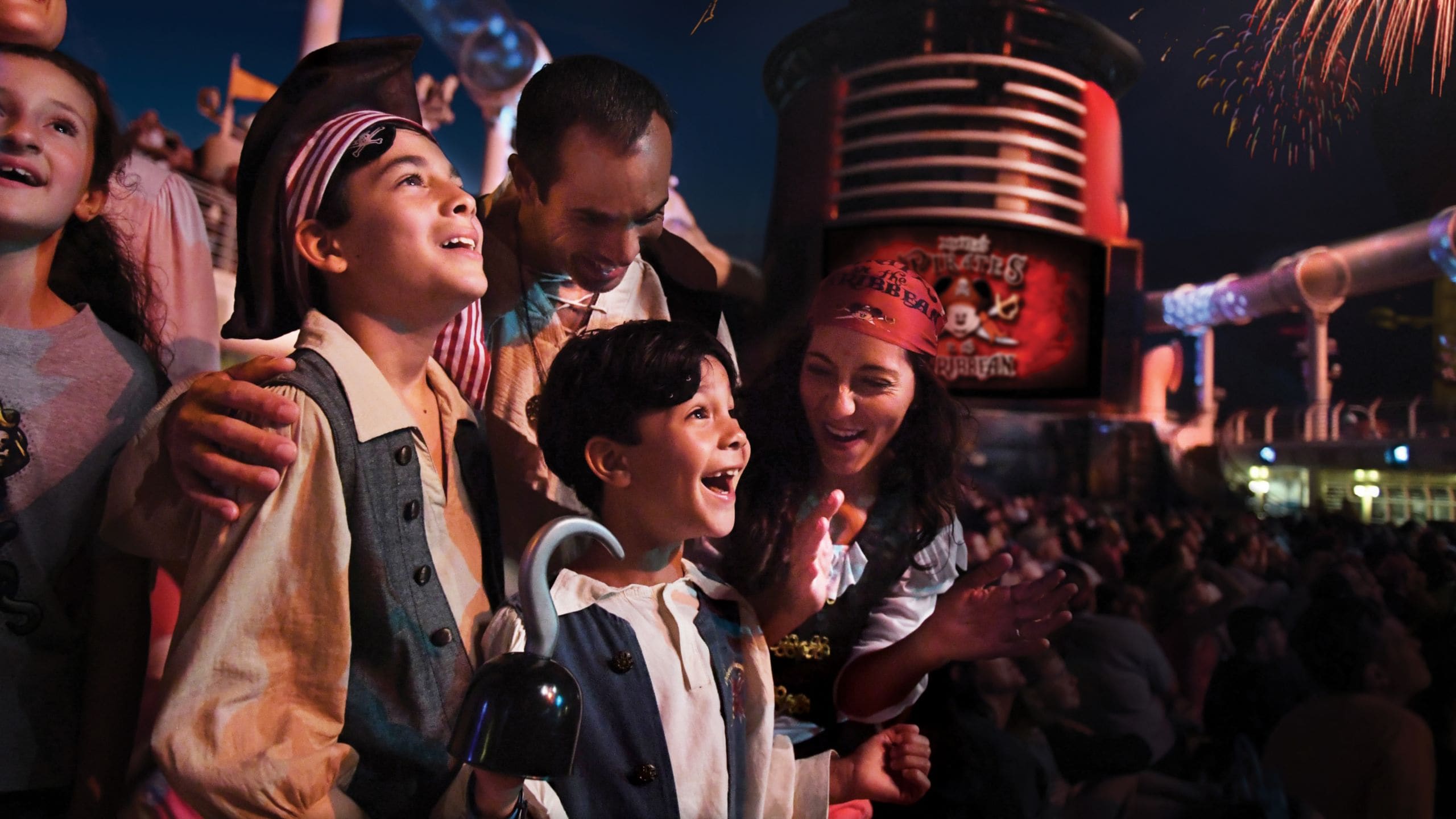 Hóspedes olhando para os fogos de artifício vestidos com trajes de pirata a bordo de um navio da Disney Cruise Line