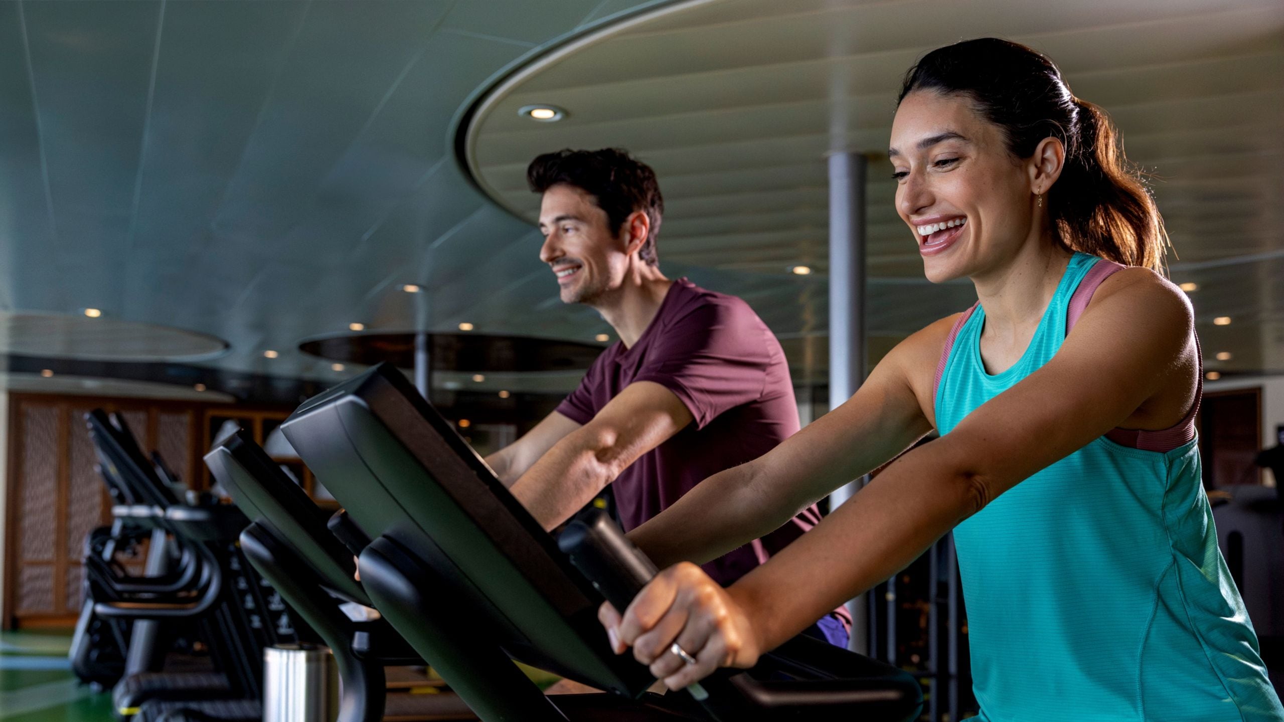A couple rides on exercise bikes in a gym