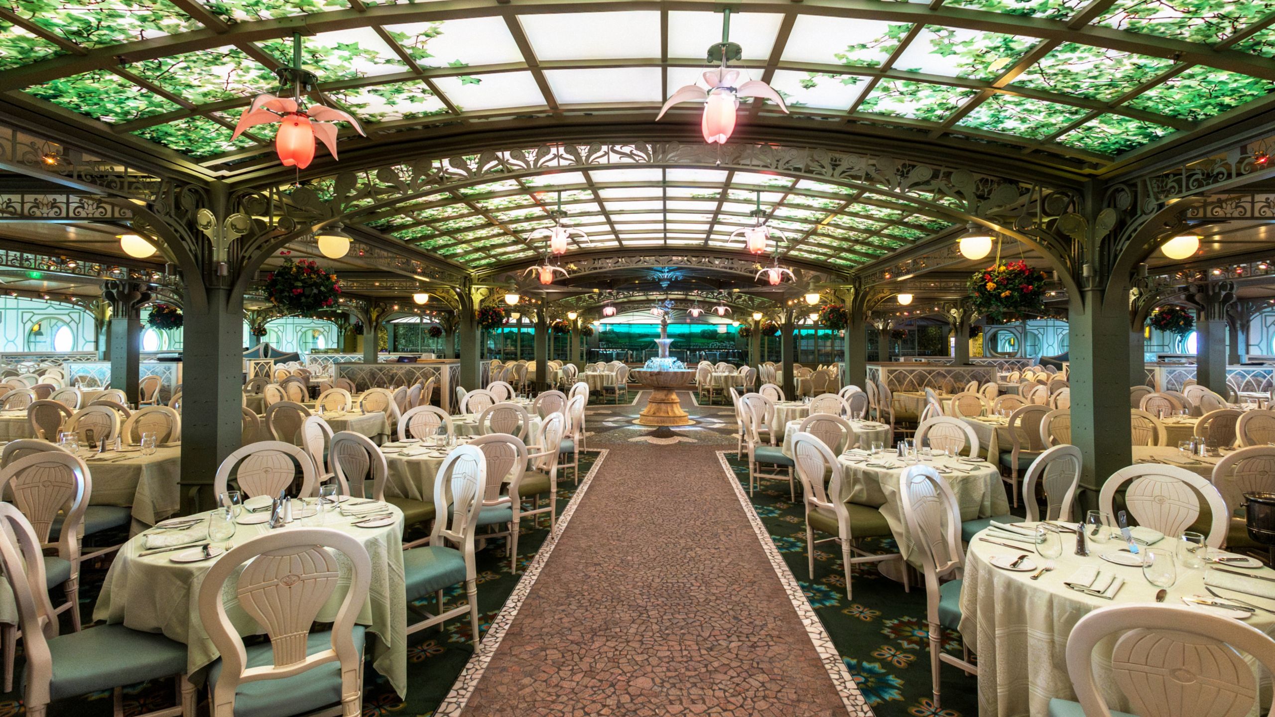 Sala de jantar no restaurante Enchanted Garden, decorada com flores suspensas e teto de vidro com pinturas