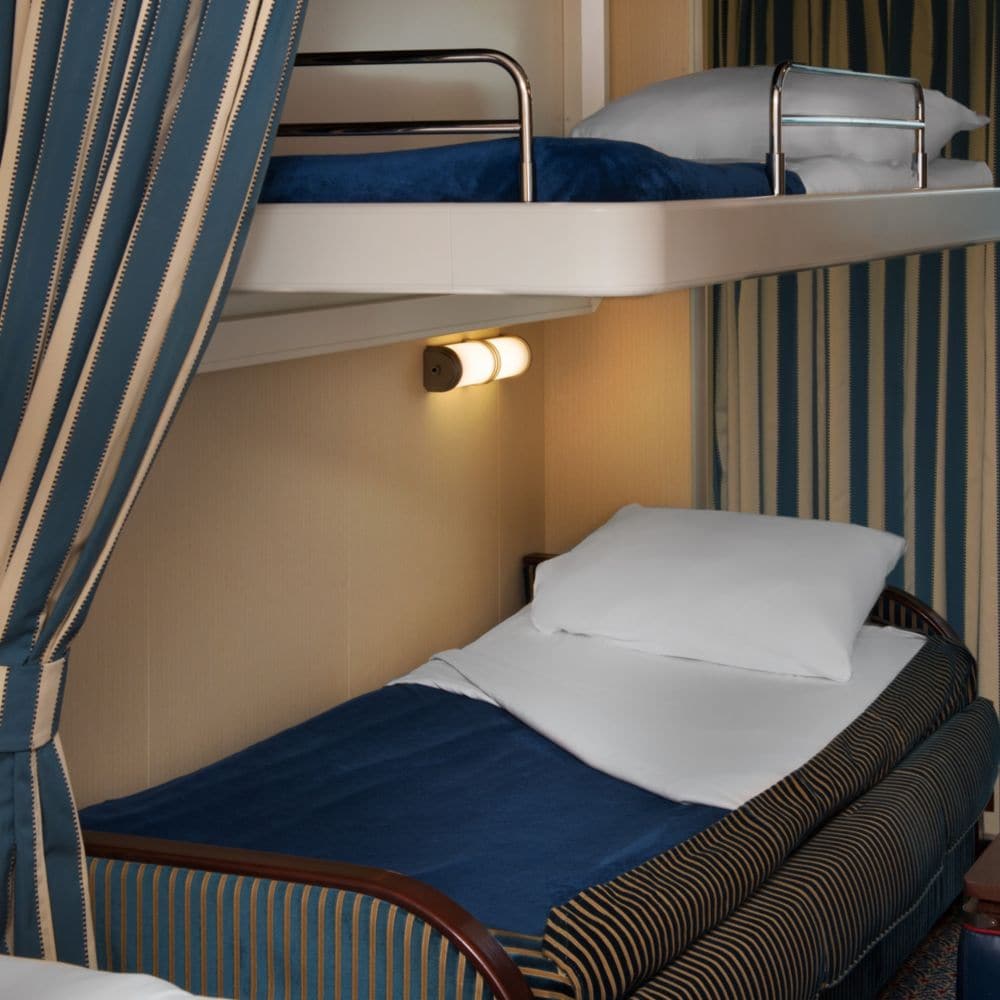A stateroom with a privacy curtain, a pull down bed and a sleeper sofa