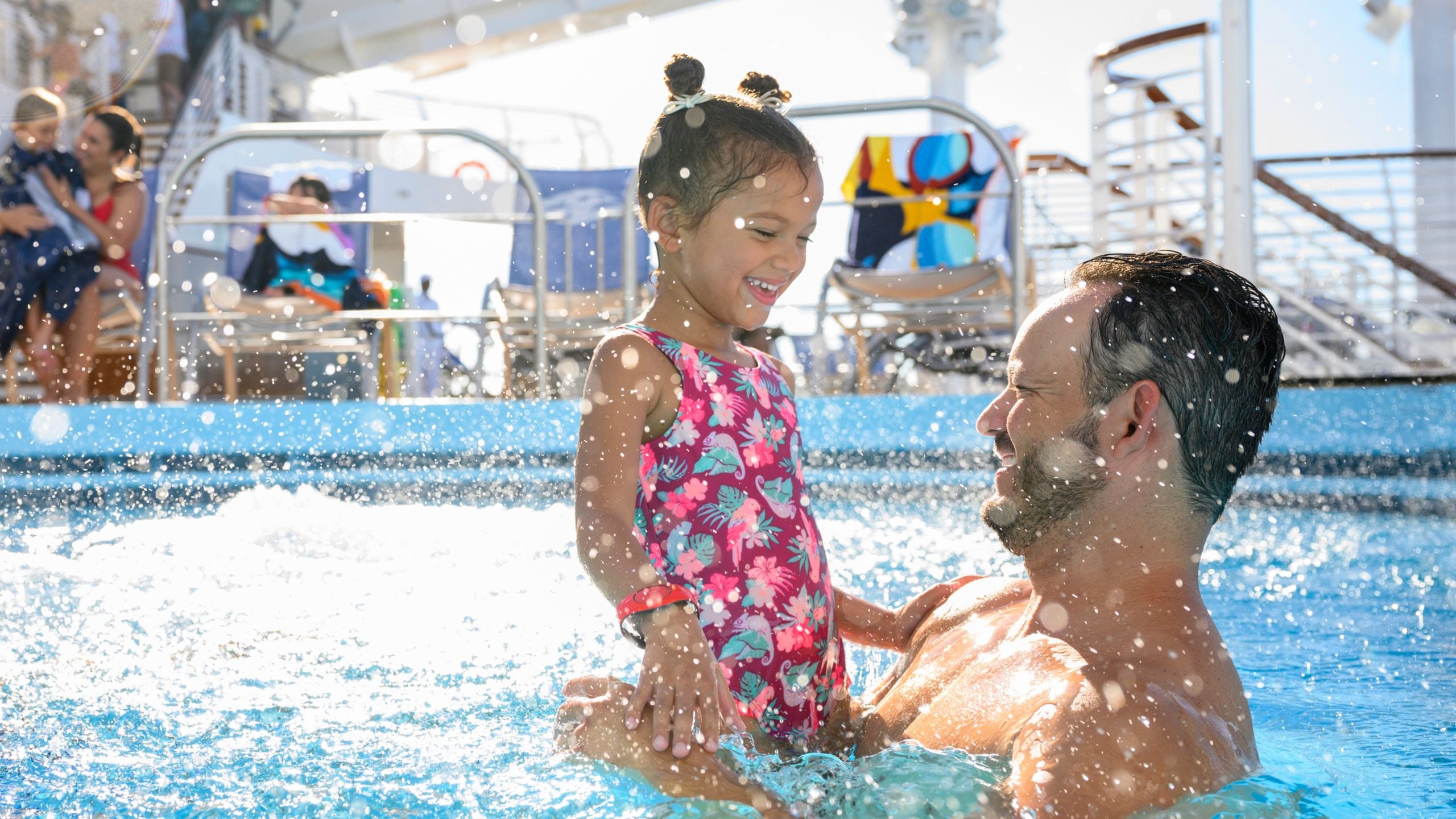 A man holding his daughter in a pool on board the Disney Wish