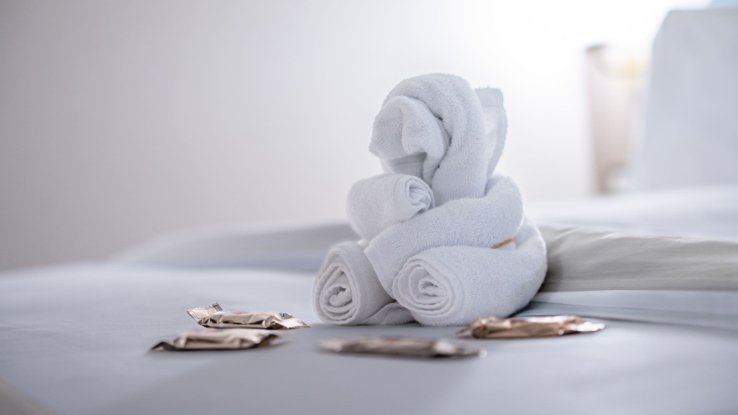 Chocolates and a decoratively folded towel in the shape of a bear on a bed in a Disney Wonder Concierge 1 Bedroom Suite with Verandah