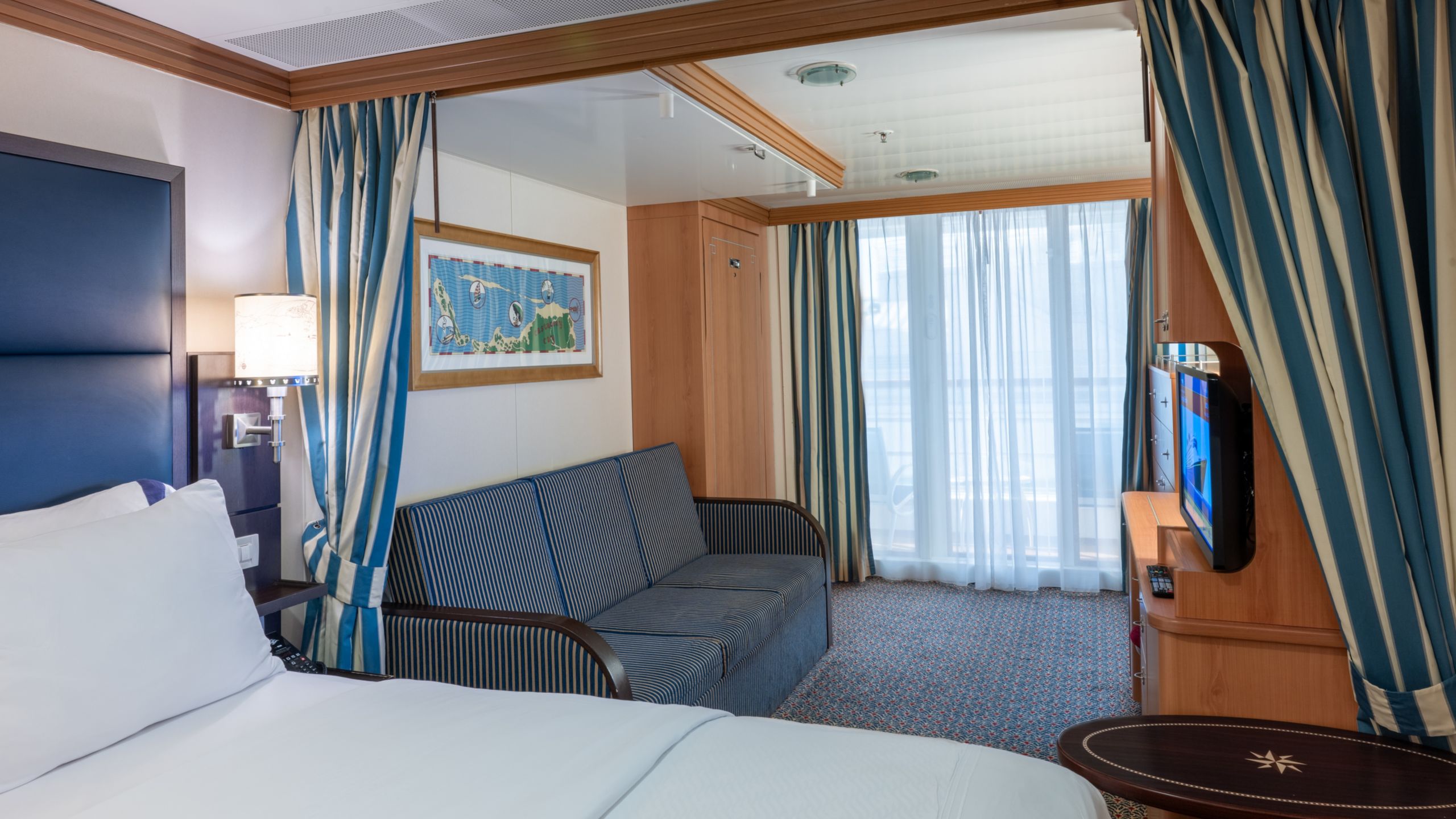 A Disney Wonder Deluxe Family Oceanview with Verandah Stateroom with a bed, table, nightstand, desk, TV, 2 bunk beds and a wall bed
