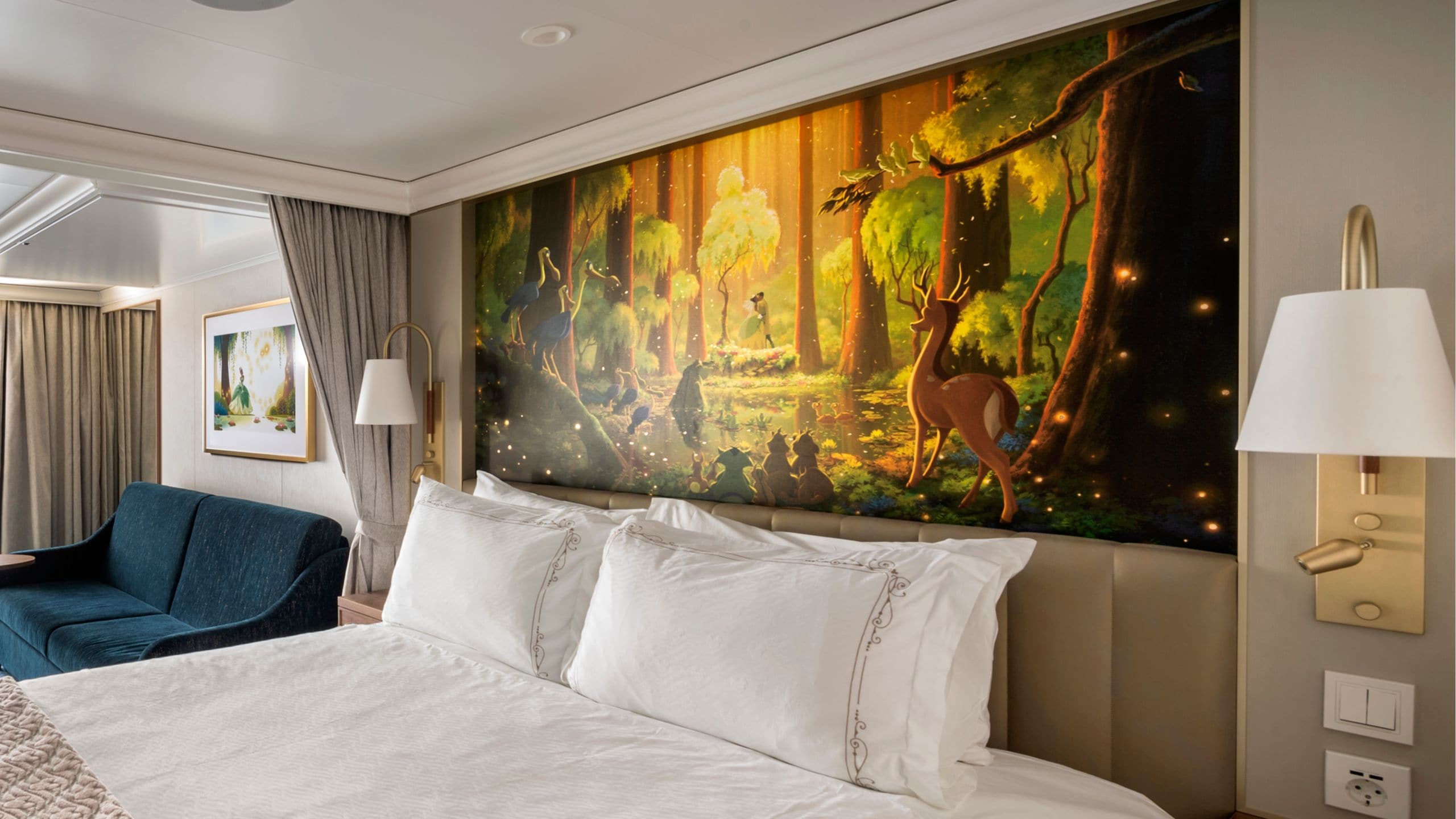 A Disney Wish stateroom featuring a bed, sofa and artwork inspired by The Princess and the Frog