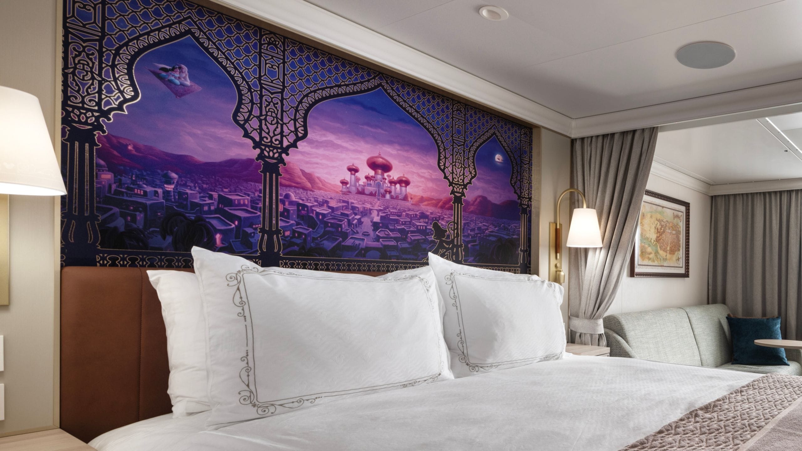 An artist rendering of a Disney Treasure stateroom with a bed and artwork inspired by Aladdin