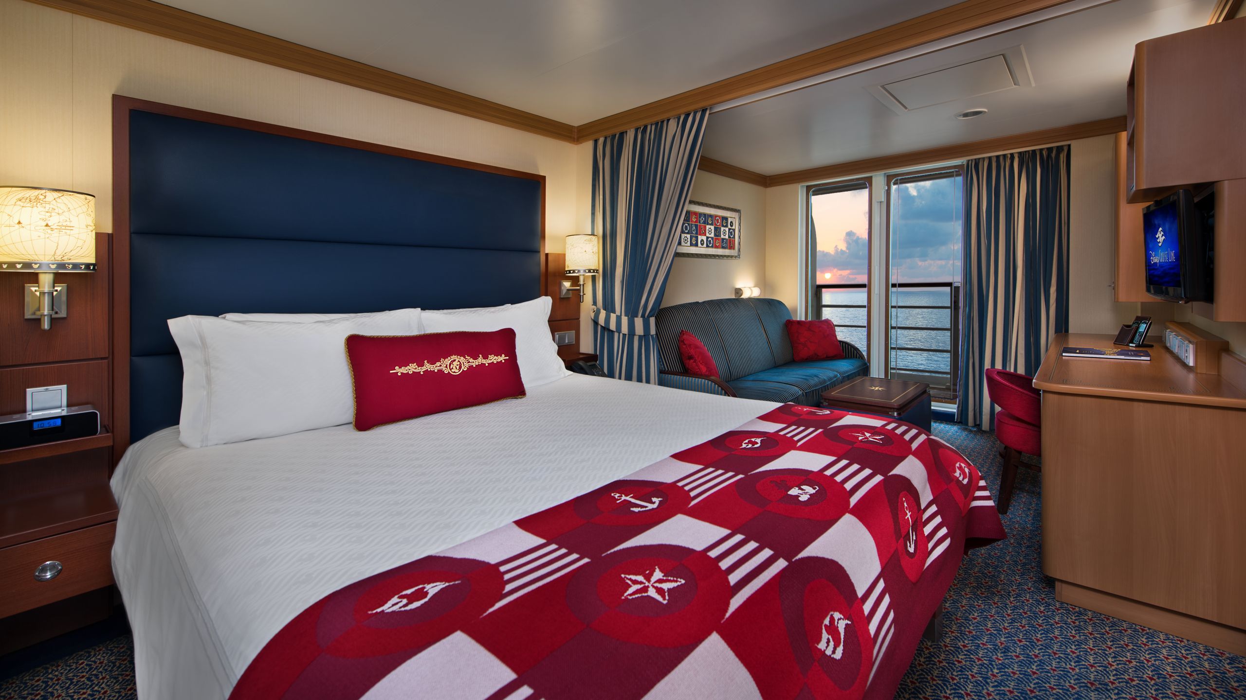 A Disney Cruise Line Deluxe Oceanview with Verandah Stateroom with a bed, a sleeper sofa, a low table, a verandah with an ocean view, a desk and a TV