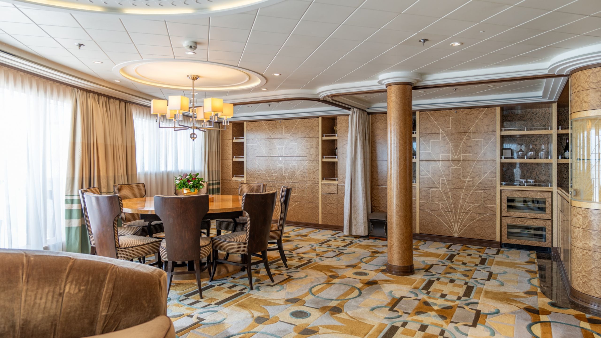 A Disney Cruise Line Concierge Royal Suite with Verandah Stateroom with a dining table, shelves and a sofa