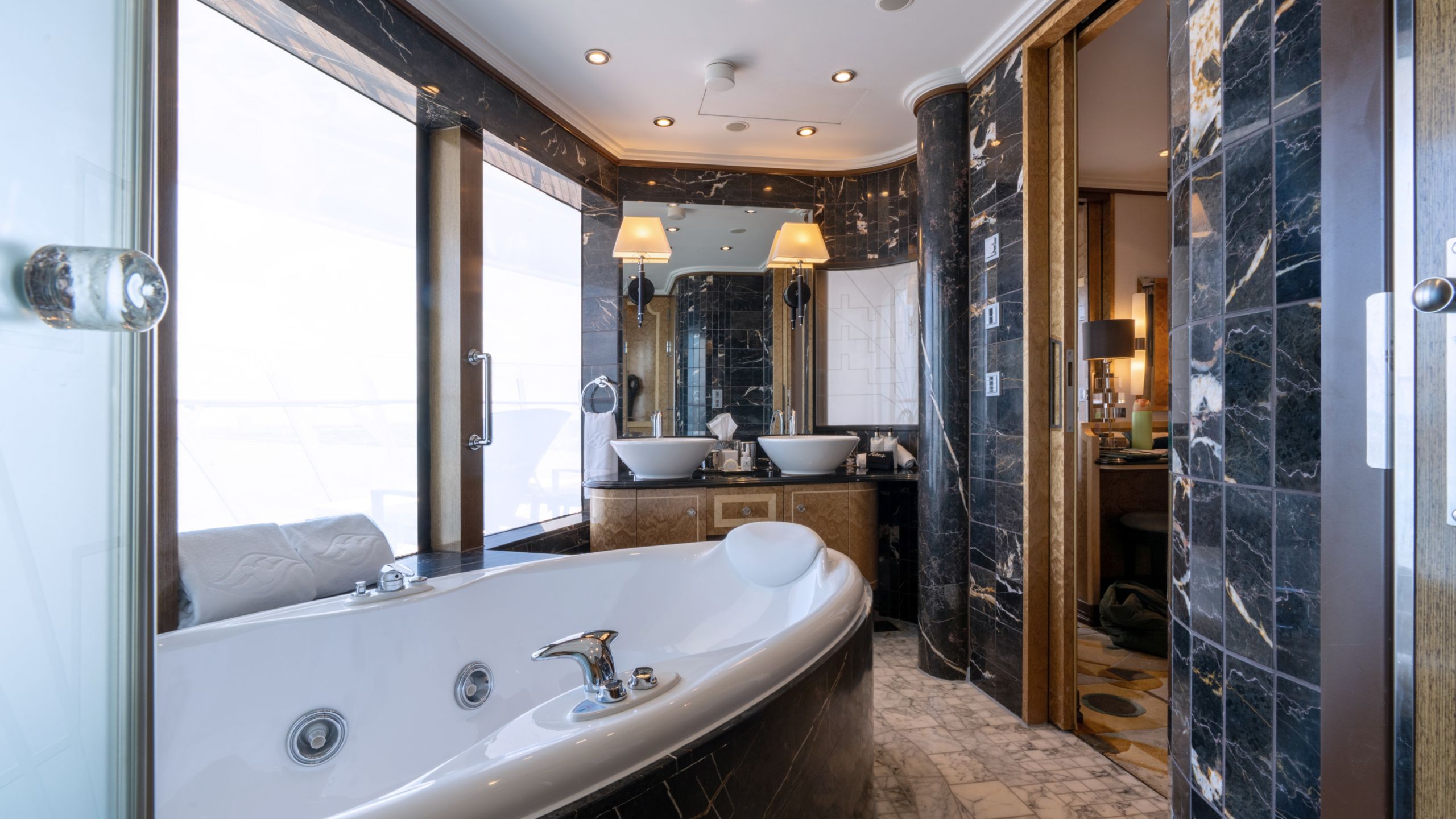 A Disney Dream Concierge Royal Suite with Verandah Stateroom bathroom with a bathtub, a window with an ocean view and 2 sinks
