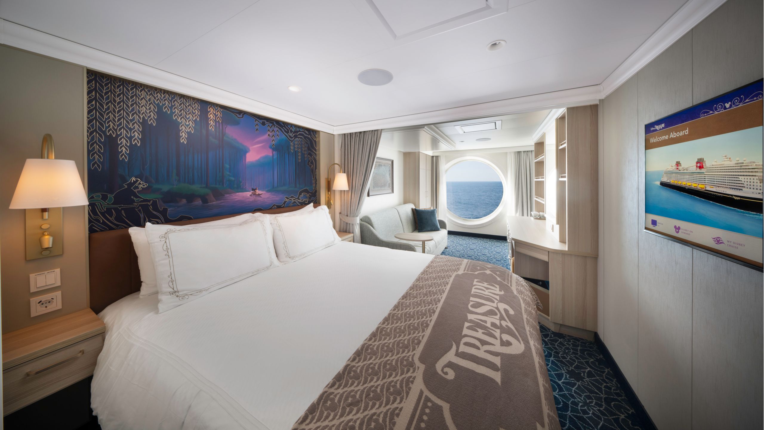 Un camarote del Disney Treasure con una cama, sofá, escritorio, dos mesas de noche, una gran portilla y obras de arte inspiradas en Pocahontas