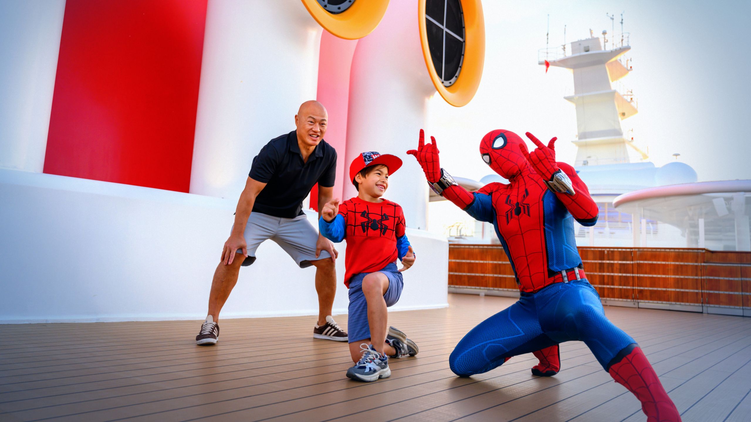 A father son posing with Spider Man on the top deck of a Disney Cruise Ship during Marvel Day at Sea