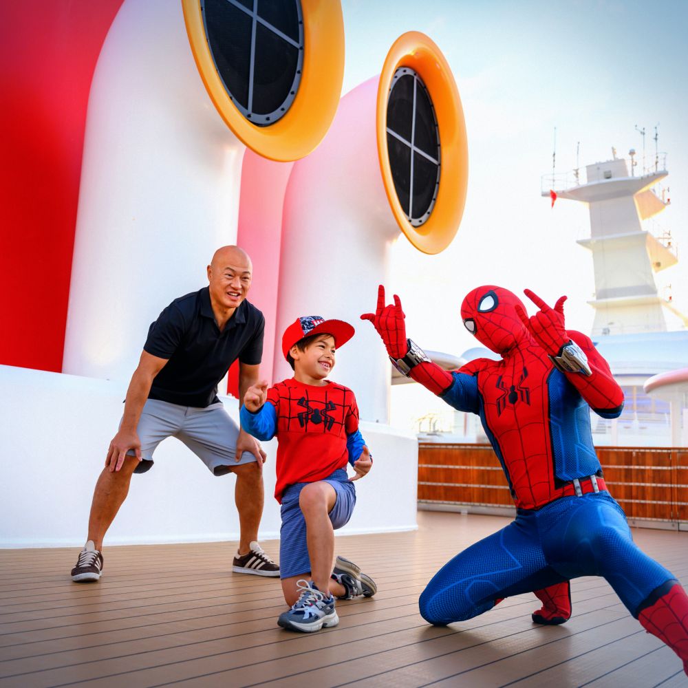 A father looks on as his small son meets Spider Man
