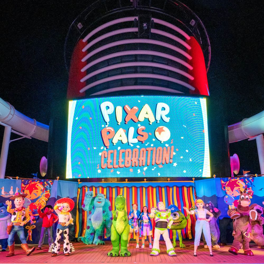 Pixar Characters waving on the deck of a Disney cruise ship with a screen that reads ‘Pixar Pals Celebration’