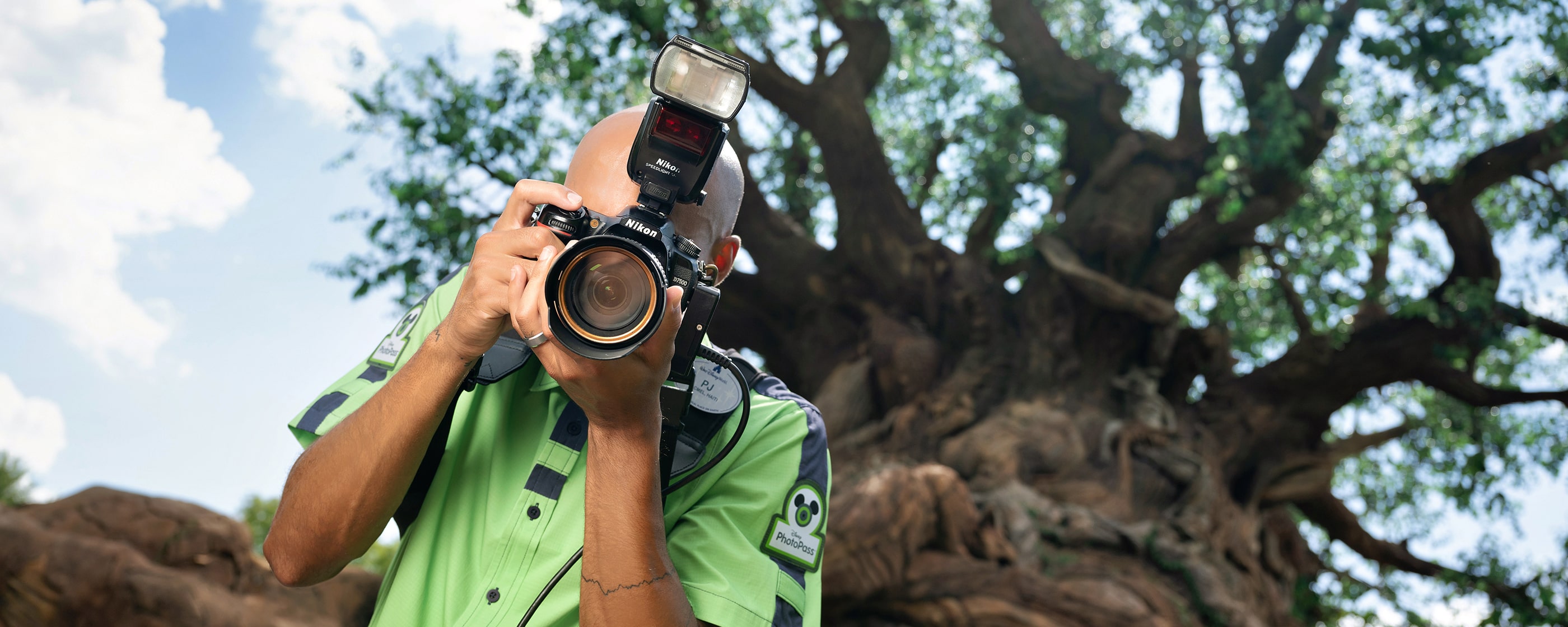 A Disney PhotoPass photographer with his camera in front of the Tree of Life at Disney's Animal Kingdom theme park