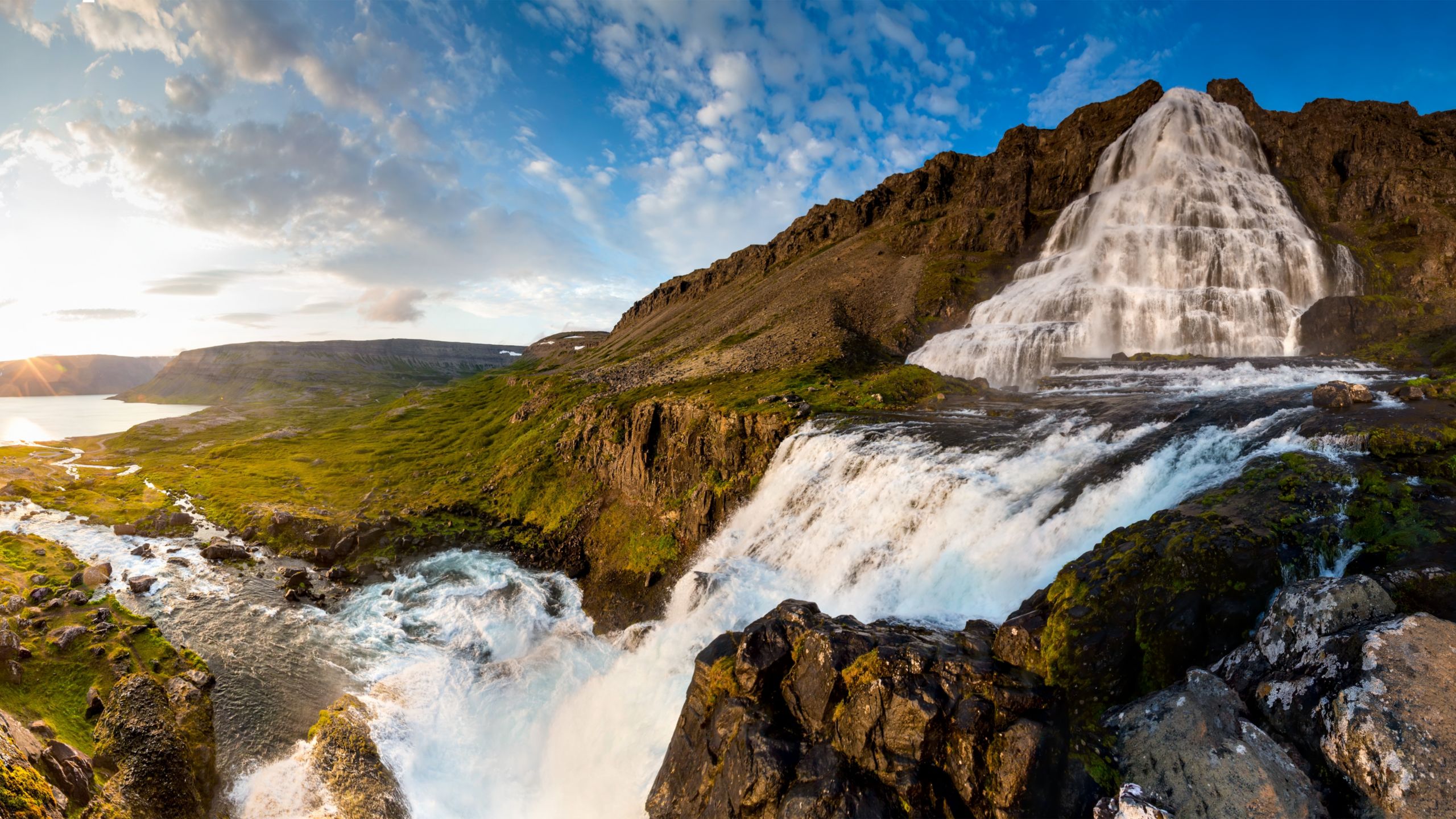 A waterfall flowing down the side of a mountain into a stream