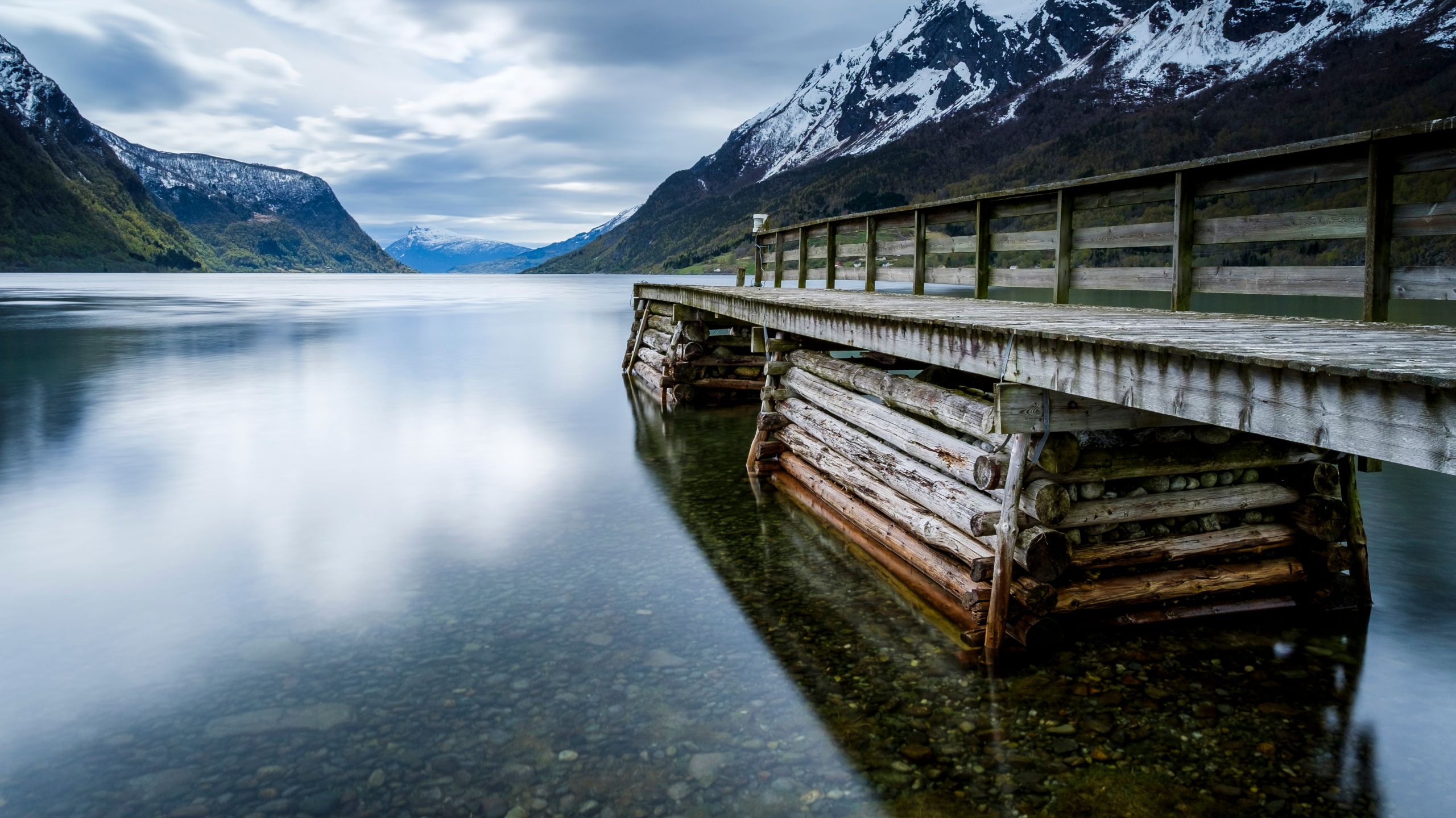 The historic Skjolden Jetty, made from weathered logs, with the mountains of the Lustrafjord