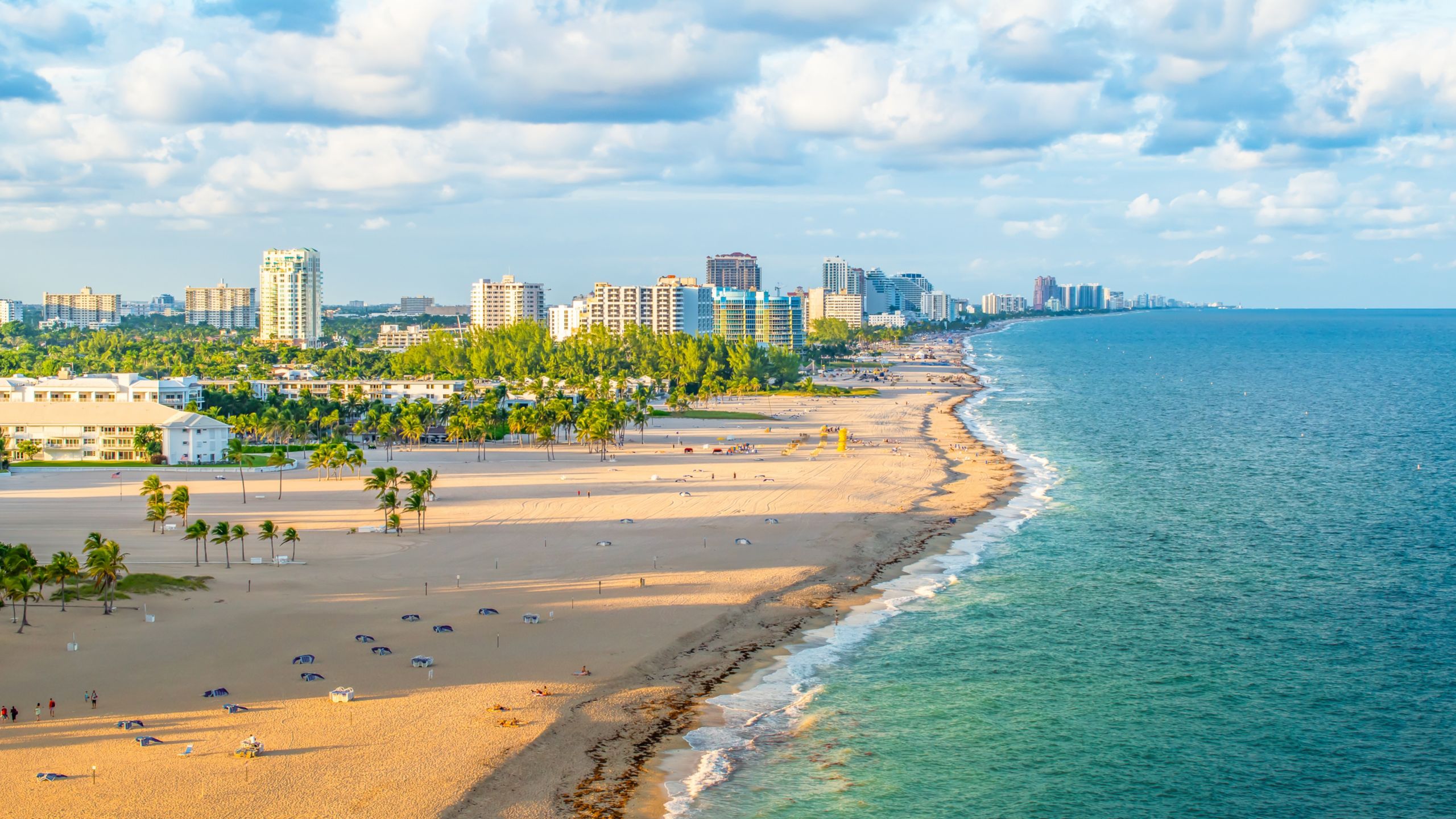 A panoramic view of a sandy beach, the ocean and a city skyline