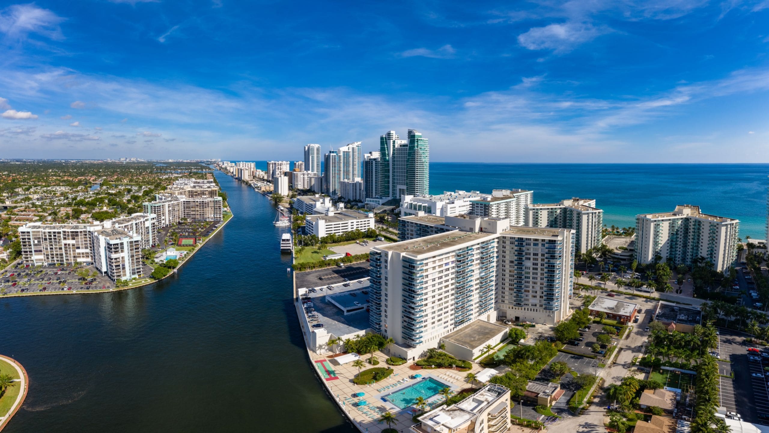 A panoramic view of high rise buildings separated by a waterway and the ocean beyond 