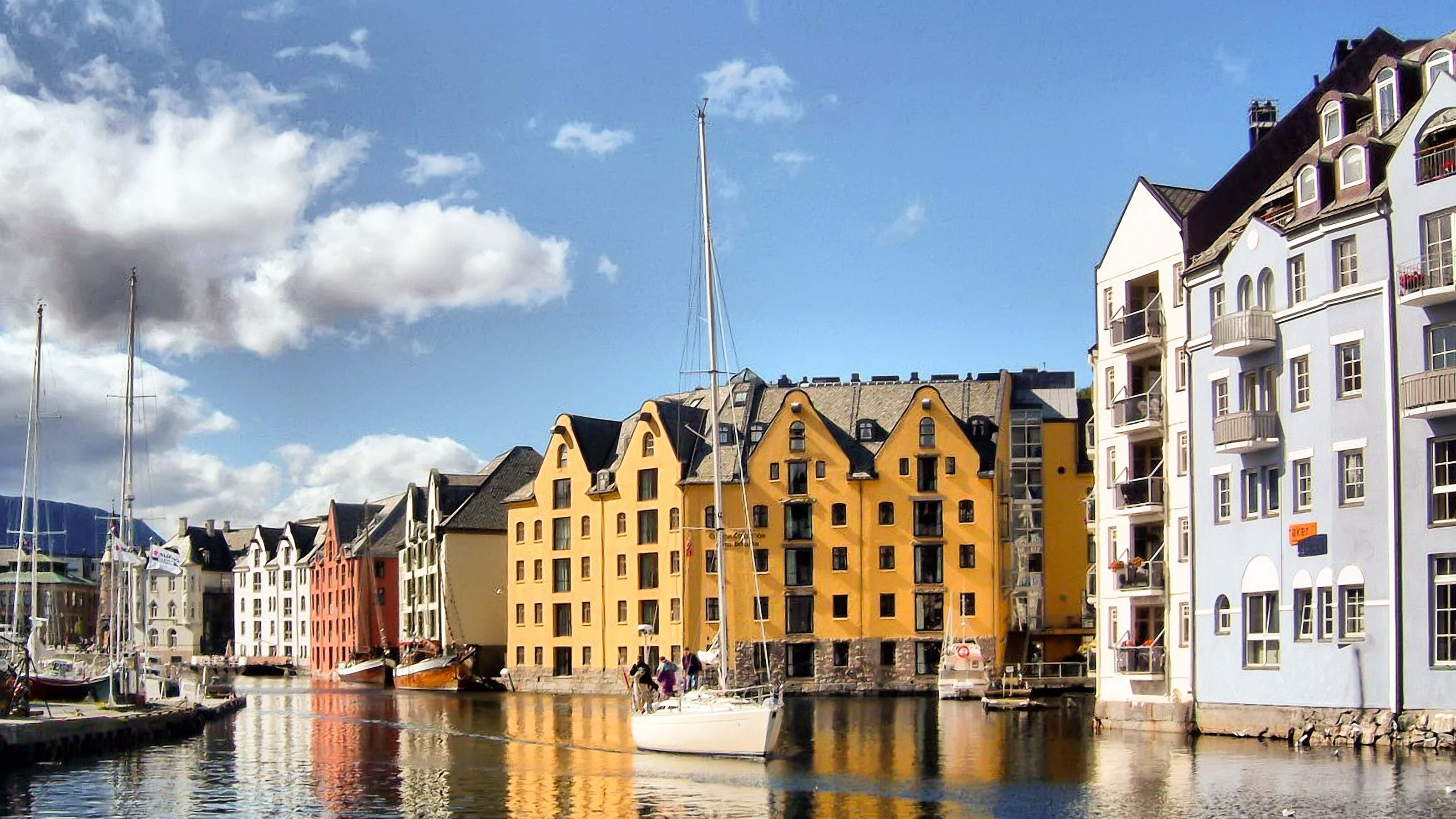 Alesund harbor with waterfront buildings, sailboats and reflections shimmering on calm water