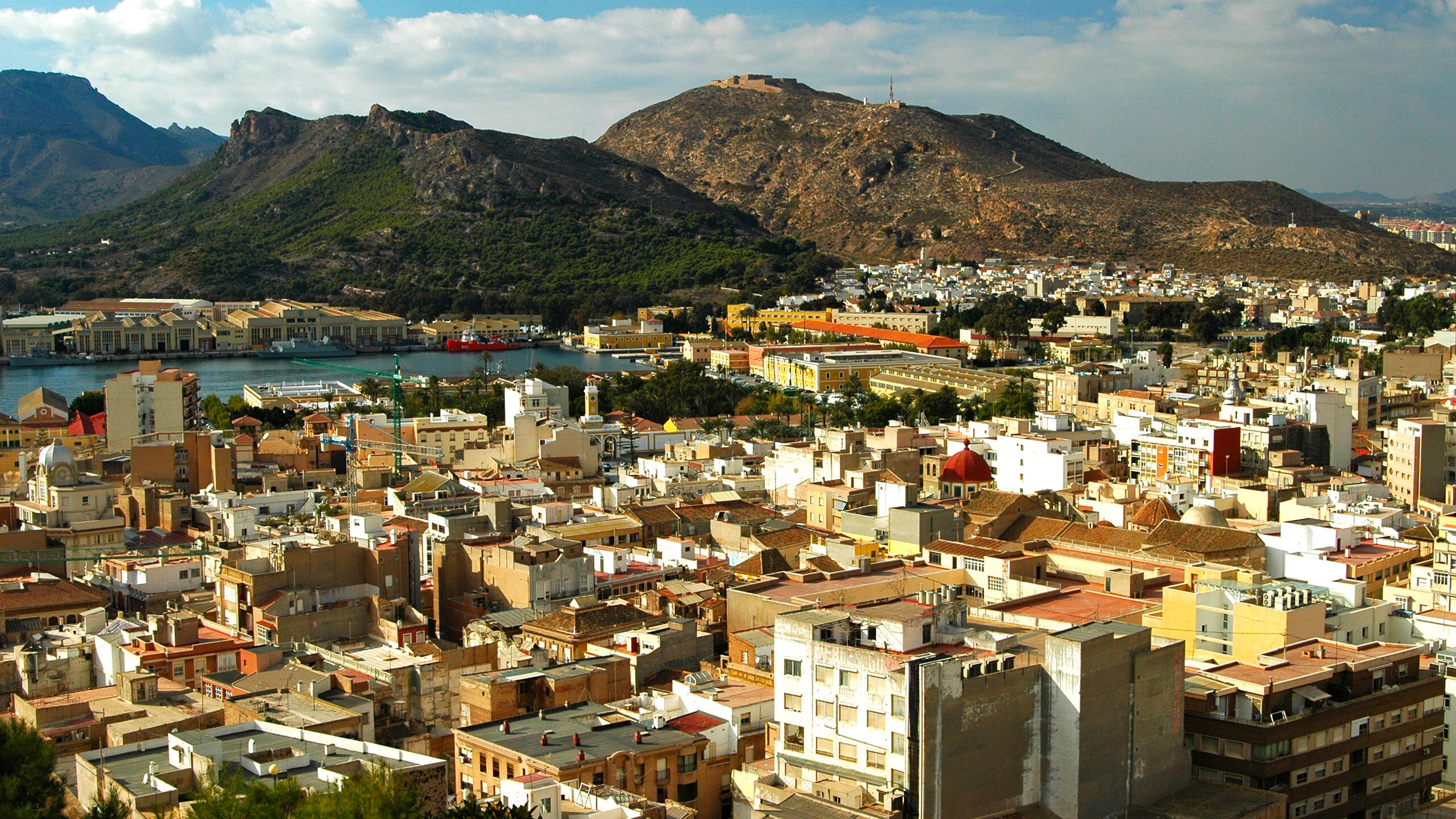 Panoramic view of Spanish coastal city Cartagena with colorful rooftops, harbor and rugged mountain backdrop