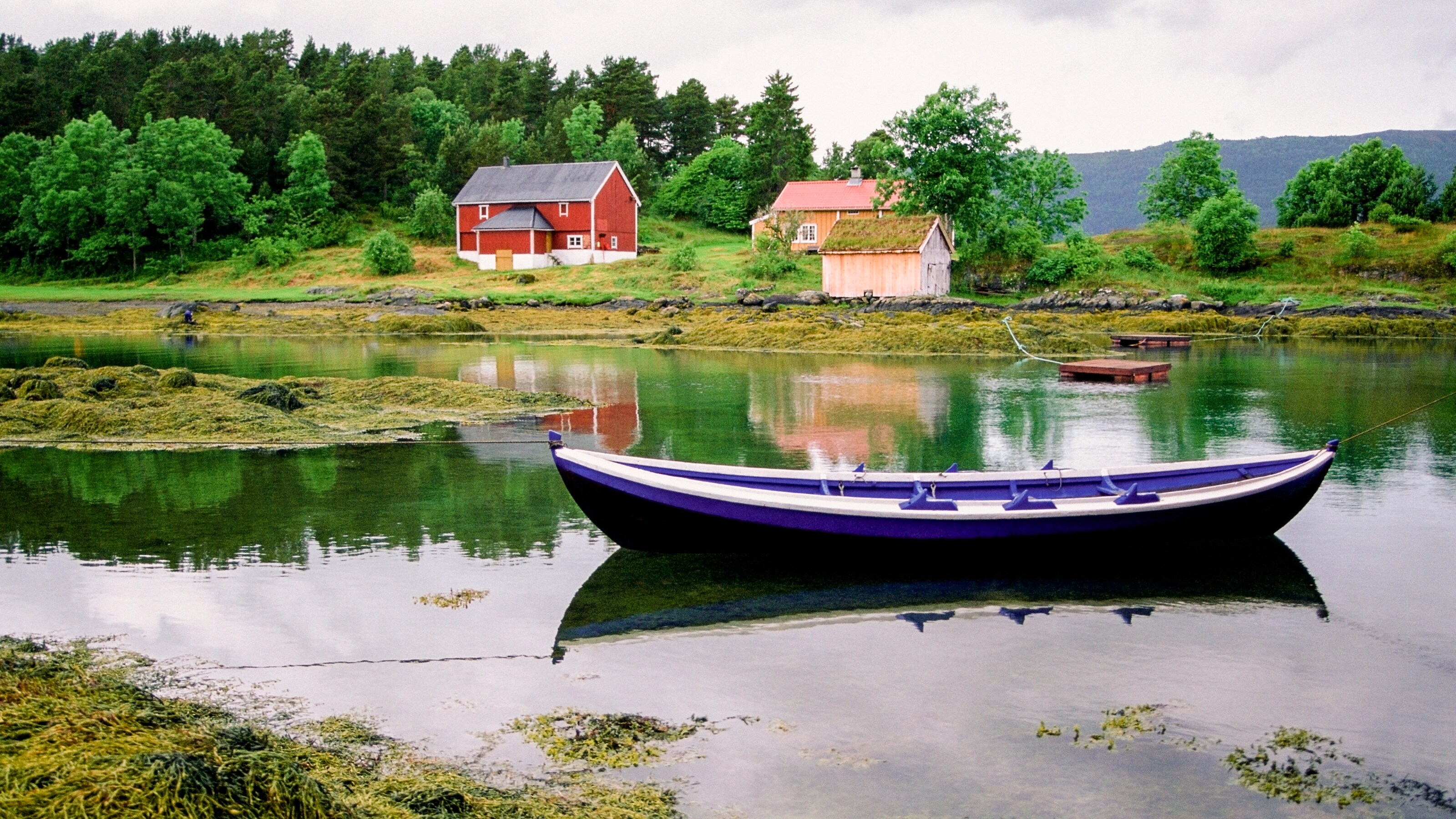 A long boat sits in the water with rope leading from either end